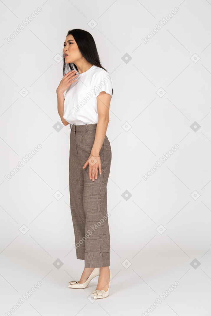 Three-quarter view of a displeased gesticulating young lady in breeches and t-shirt