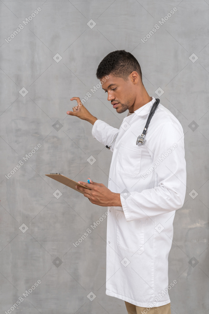Arzt mit stethoskop schaut auf die zwischenablage und gestikuliert