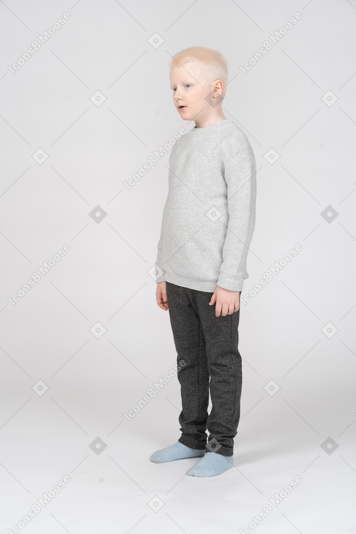 Three-quarters view of a kid boy in casual clothes looking surprisingly