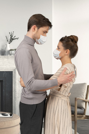 A man and a woman wearing masks in a living room