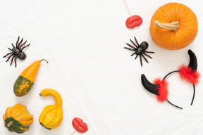 Different pumpkins, toy spiders, lollipops and a headband with horns