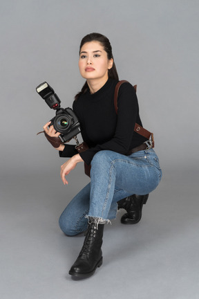 Young woman staying on her knees and holding camera