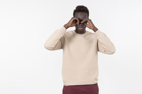 A young black man in a grey sweater standing alone on the white background