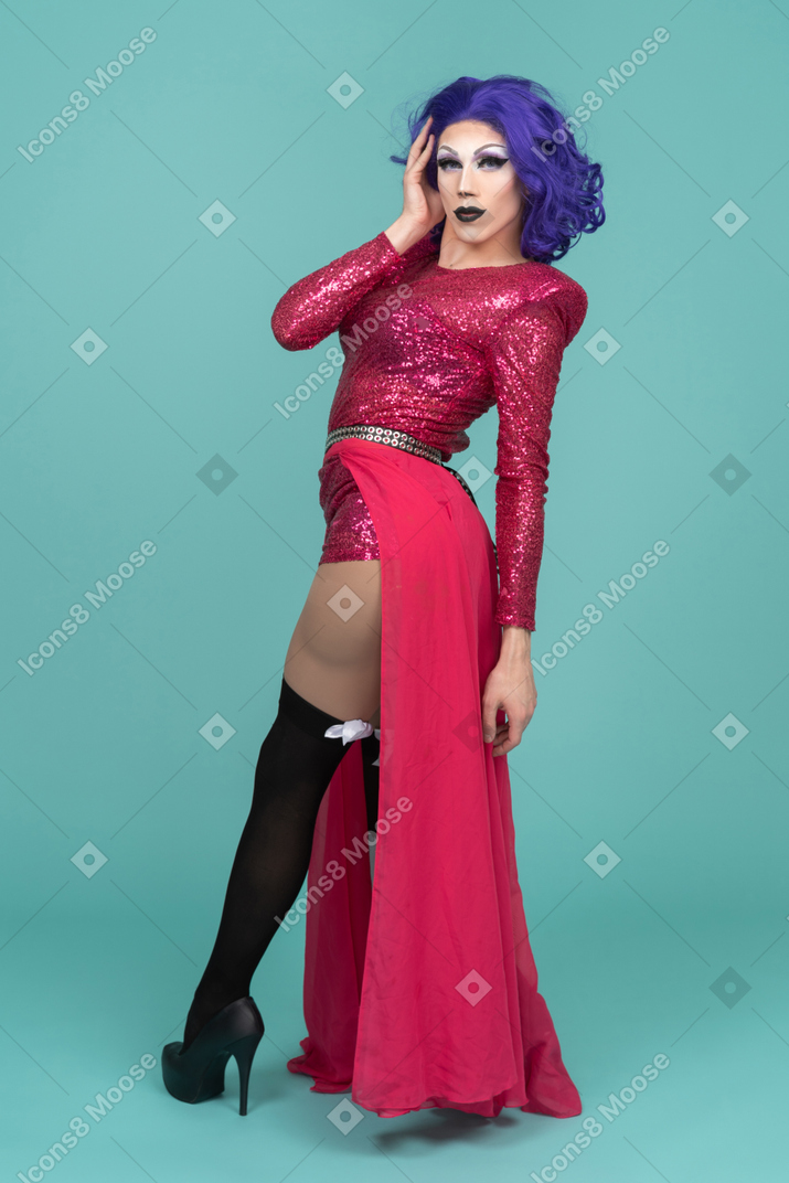 Drag queen in pink dress turning around with hand next to face