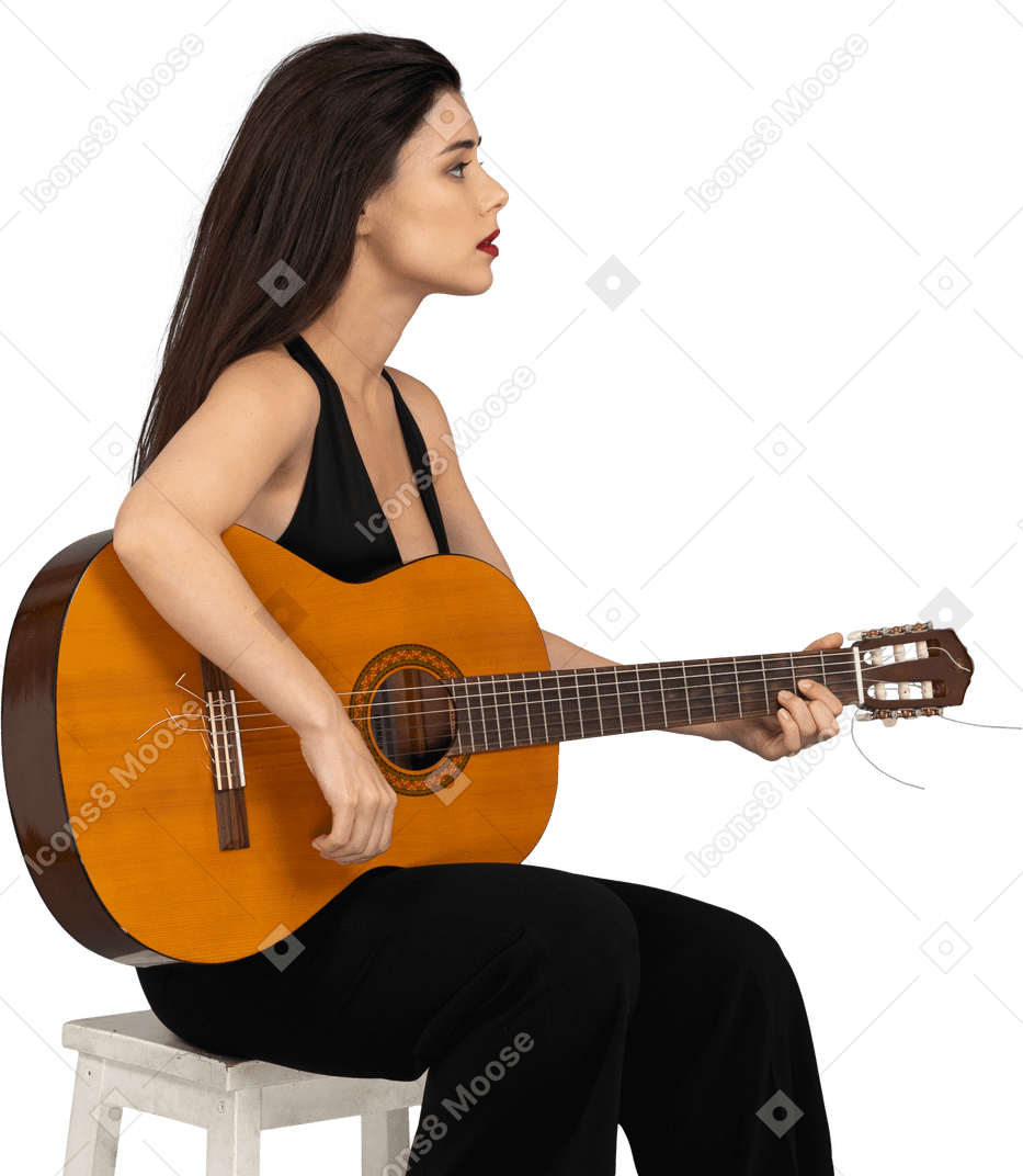 Vista de tres cuartos de una joven sentada en traje negro tocando la guitarra