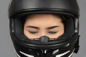 A woman with closed eyes wearing a black helmet