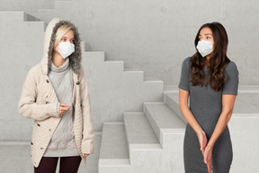 Two girls standing near a ladder and wearing masks