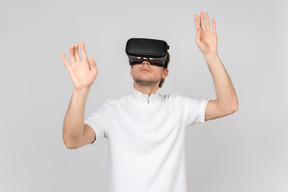 Young man in virtual reality headset touching something invisible