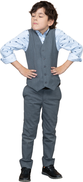 Vista frontale di un ragazzo carino in giacca e cravatta in posa con le mani sui fianchi