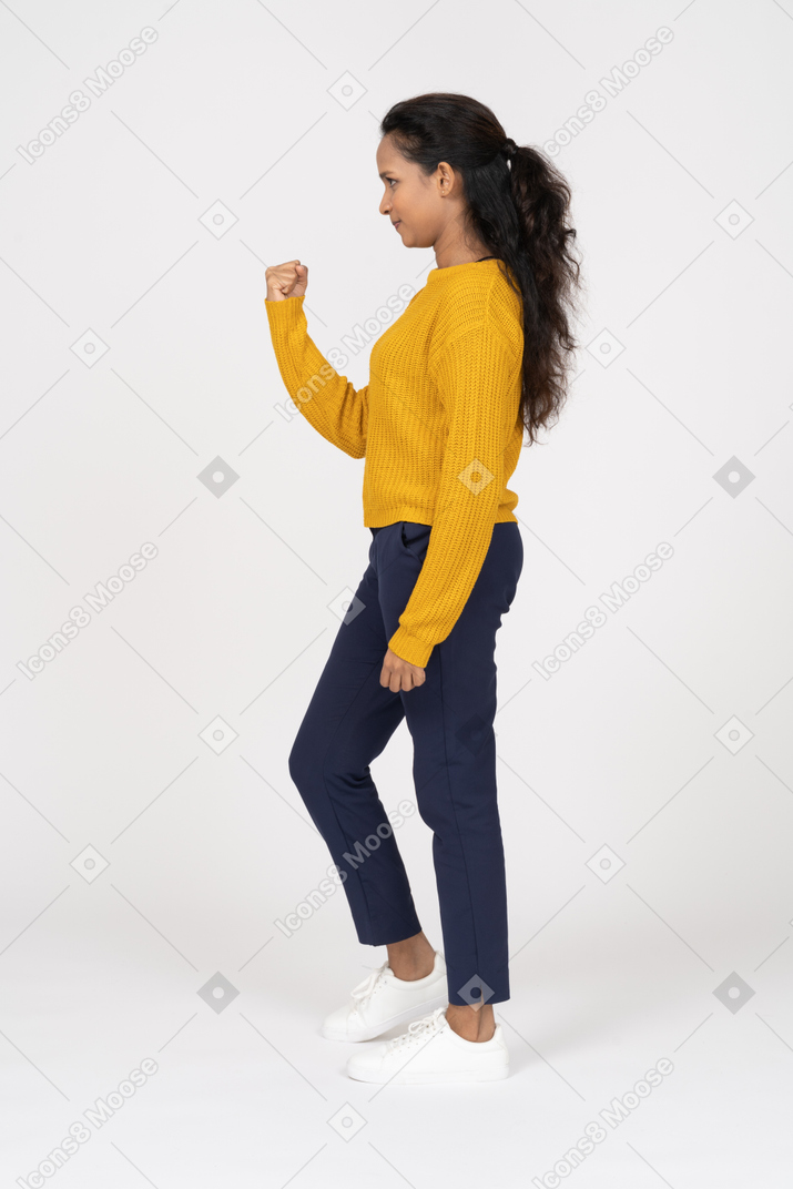 Side view of a girl in casual clothes threatening with a fist
