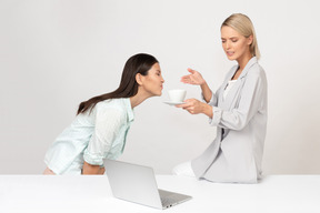 Donna attraente che si lamenta del gusto del suo caffè mentre il suo collega si sta chiaramente godendo il suo aroma