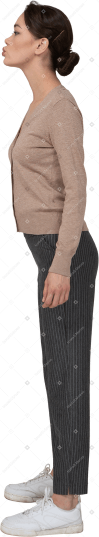 Vue latérale d'une jeune femme boudeuse en pull et pantalon