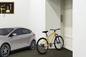 A white car parked next to a yellow bike