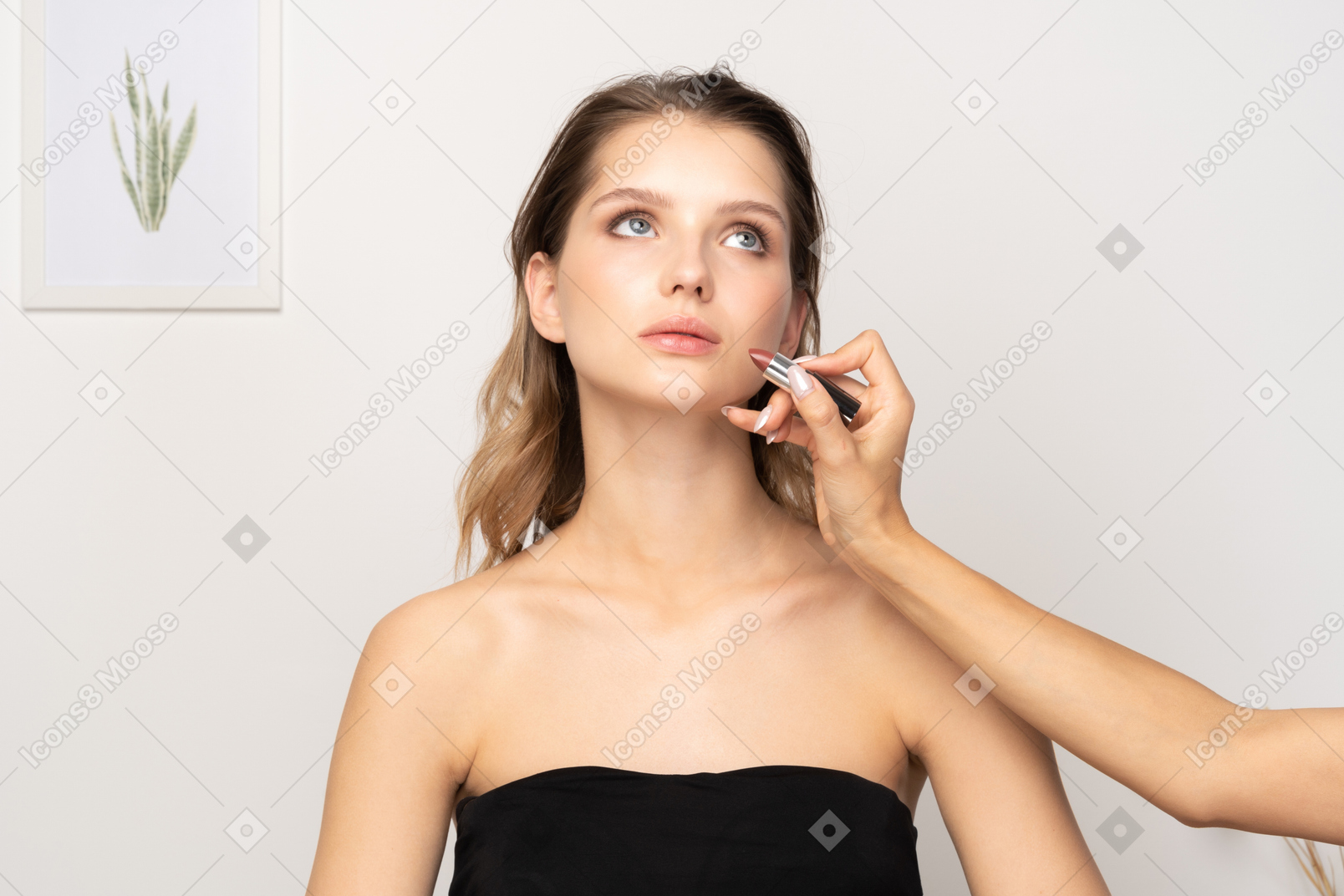 Vista frontal de un maquillador aplicando lápiz labial para un modelo femenino