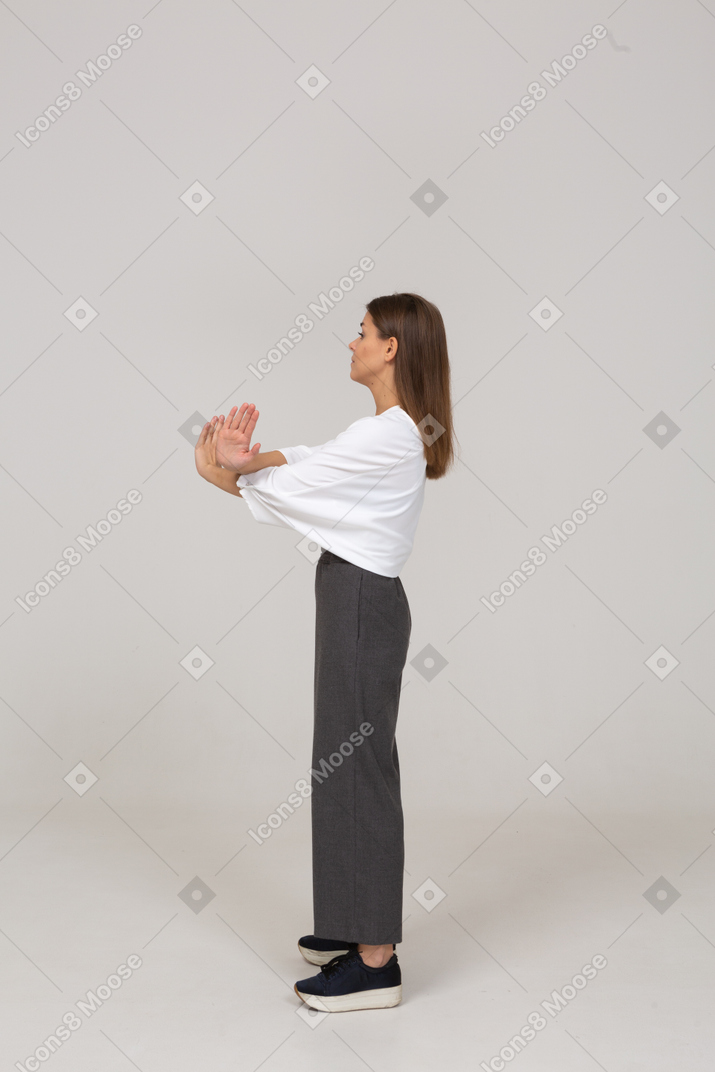 Vista lateral de una señorita en ropa de oficina cruzando los brazos