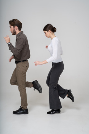 Side view of a young couple in office clothing raising leg