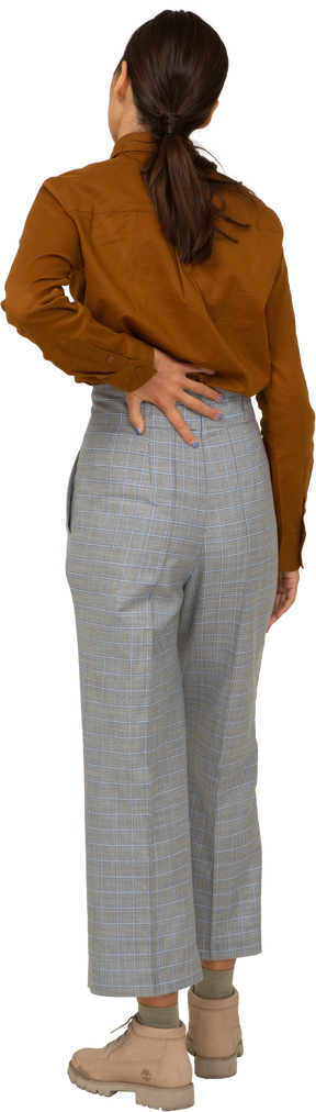 Vista posteriore di una giovane donna asiatica in calzoni e camicetta che si tocca la schiena