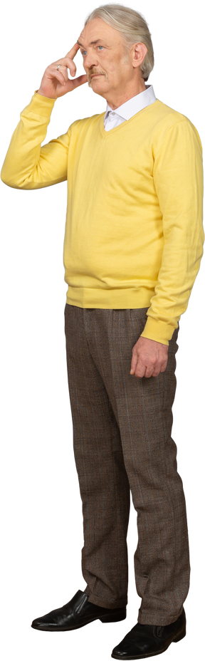 Three-quarter view of an old thoughtful man wearing yellow pullover and touching forehead