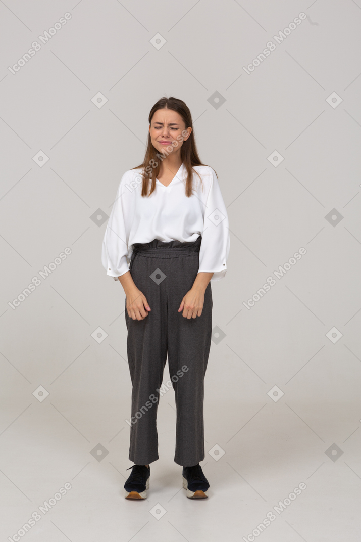Front view of an upset young lady in office clothing standing with her eyes closed