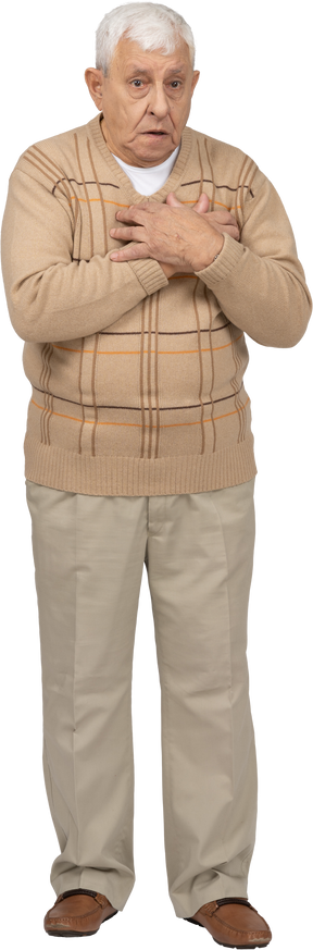 Front view of a scared old man in casual clothes standing with hands on chest