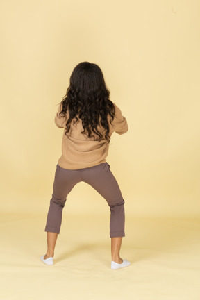 Back view of a squatting dark-skinned young female with her legs widespread