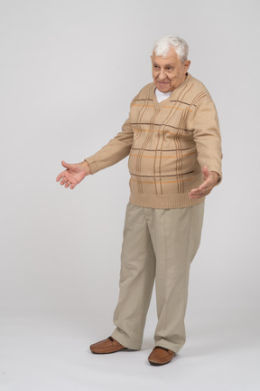 Vorderansicht eines glücklichen alten mannes in freizeitkleidung, der mit ausgestreckten armen steht