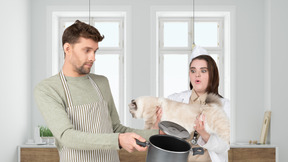 A woman holding a cat and a man with an empty pot