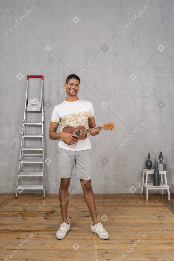 Vue de face d'un homme jouant du ukulélé et souriant joyeusement