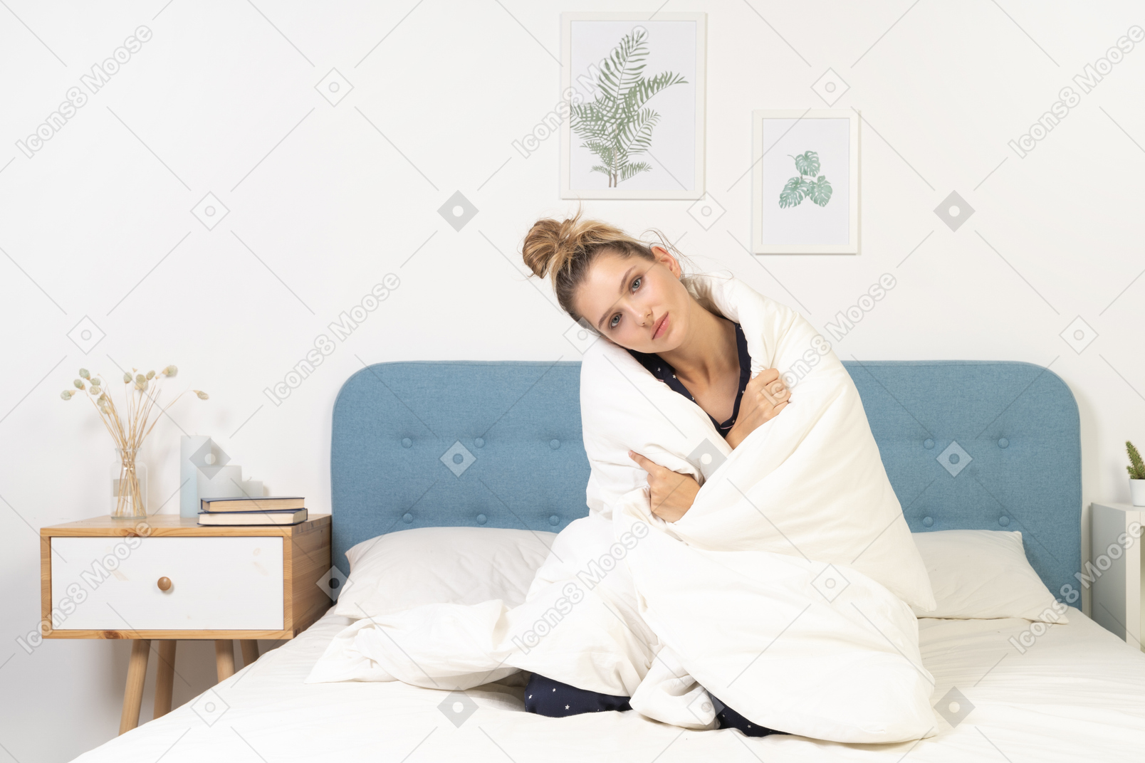 一个穿着睡衣、裹着毯子的疲惫年轻女子躺在床上的前视图