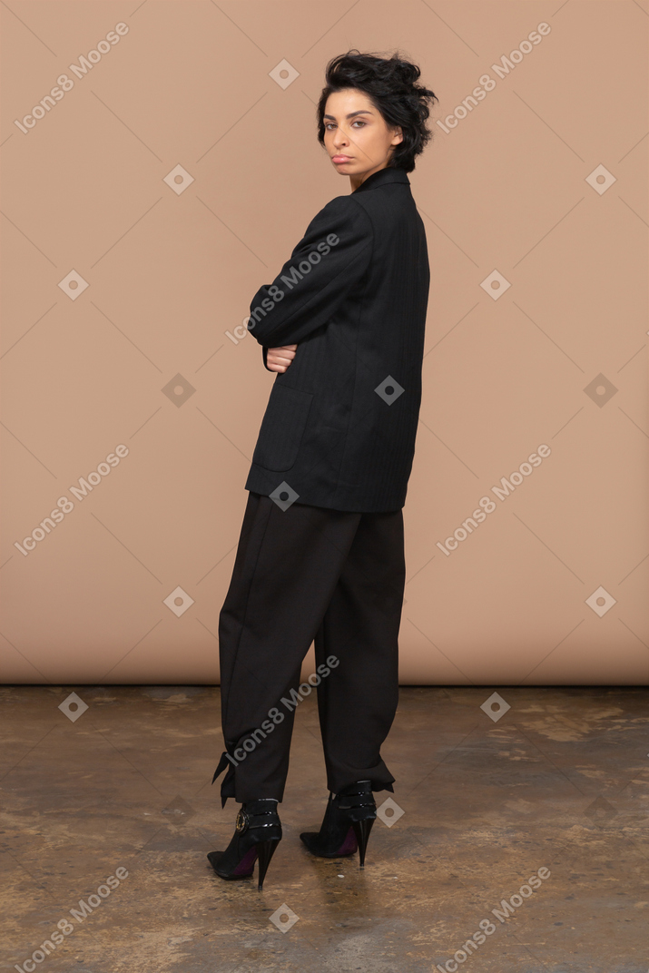 Three-quarter view of a naughty businesswoman in a black suit pouting and looking at camera
