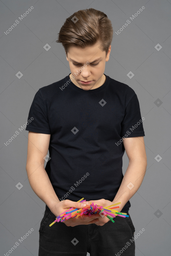 Jeune homme essayant de compter les pailles en plastique