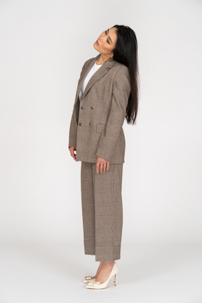 Three-quarter view of a young lady in brown business suit tilting head