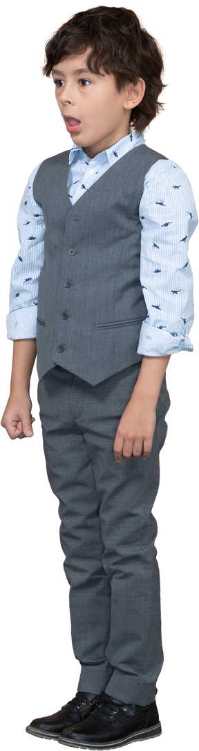 Вид спереди симпатичного мальчика в сером костюме, стоящего с открытым ртом
