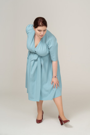 一个穿着蓝色连衣裙的女人弯下腰的前视图