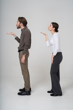 Vista laterale di una giovane coppia in abiti da ufficio inviando un bacio d'aria