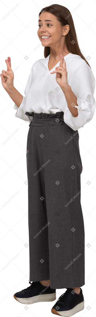 Three-quarter view of a young lady in office clothing crossing fingers