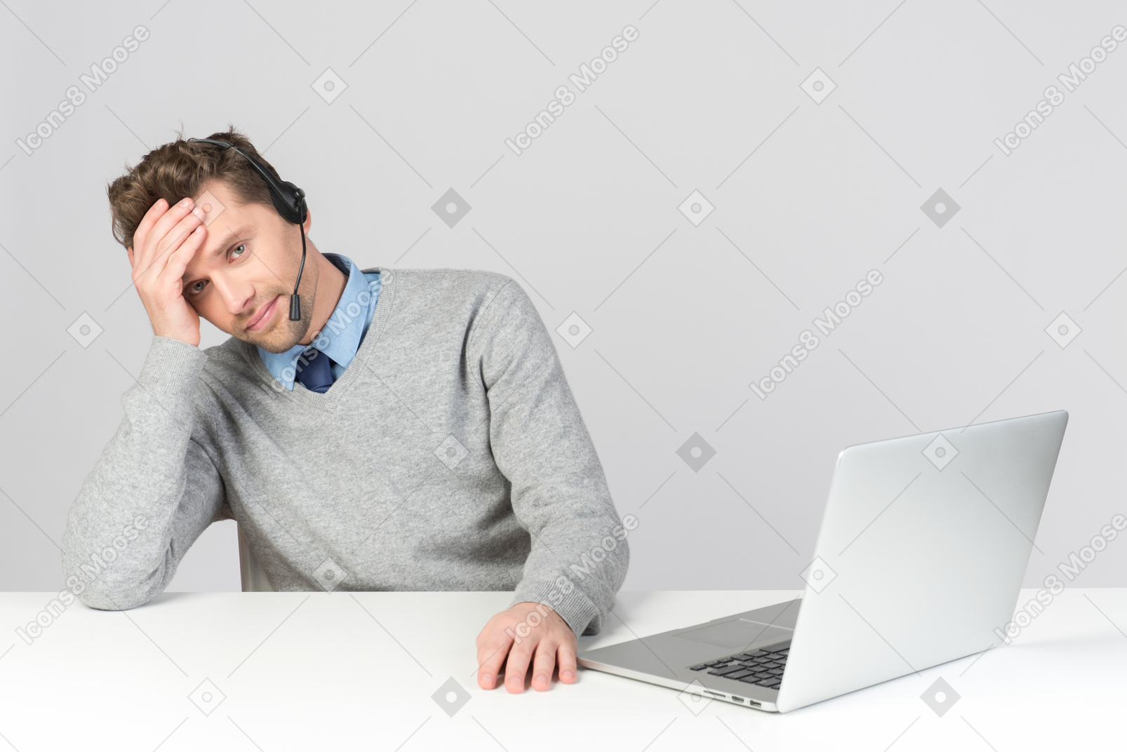 Call center operator sitting at office desk and leaning head on hand