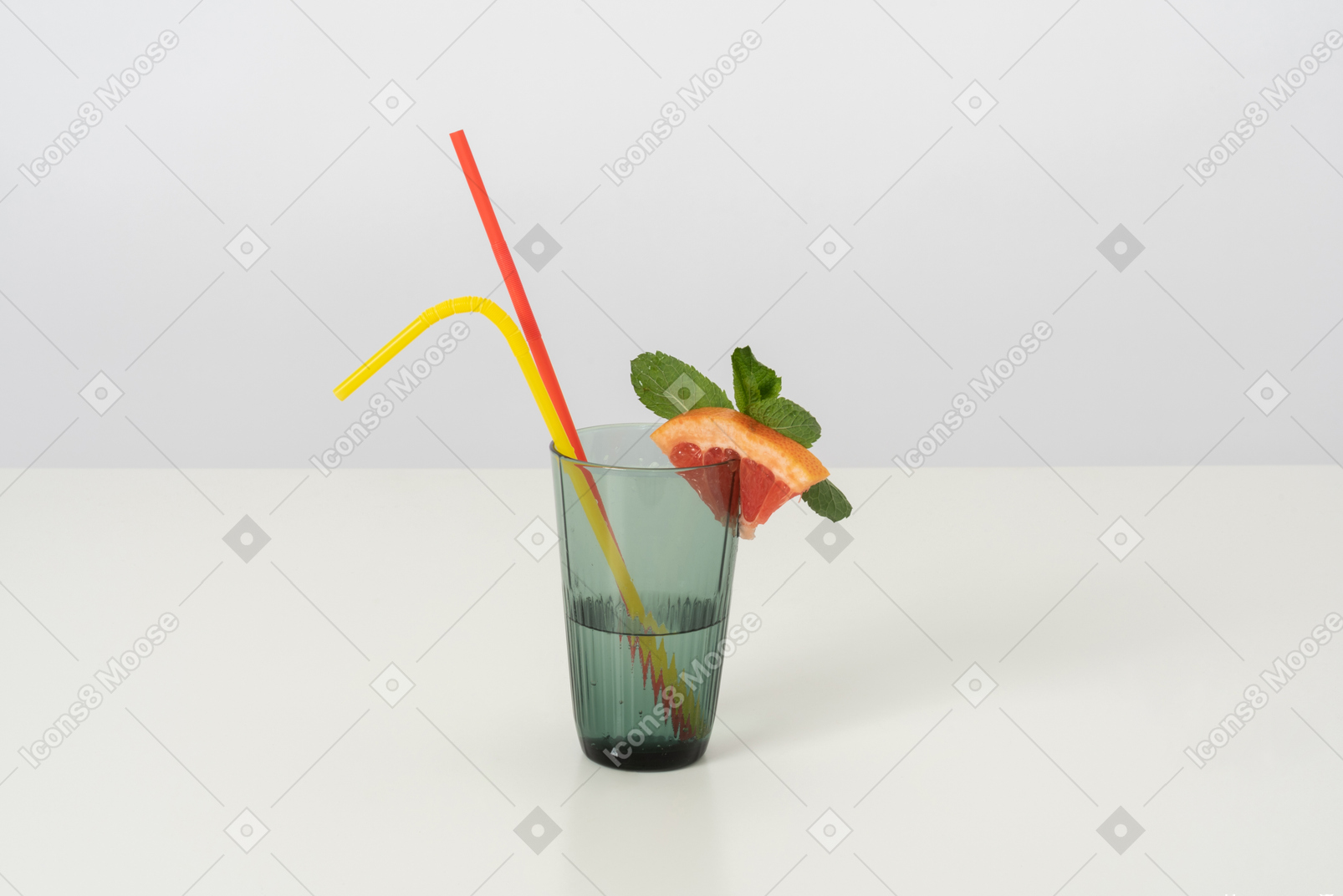 A glass of cold water with a slice of grapefruit and some mint leaves on it, with two colorful plastic straws because drinking from both at the same time is double fun