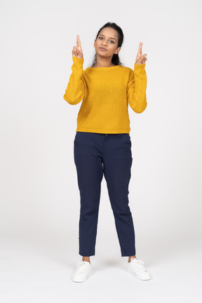 Front view of a girl in casual clothes pointing up with fingers