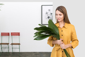 A woman holding a large green plant in her hands