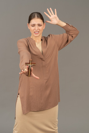 Christian woman holding a cross and throwing her arm up