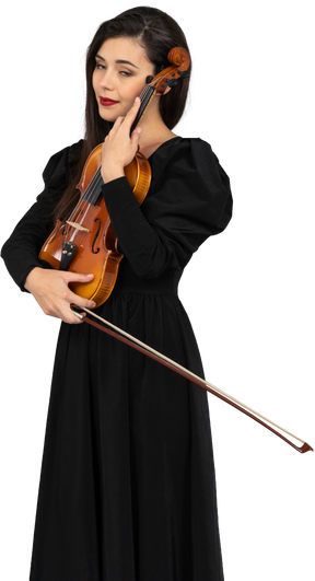 Primo piano di una giovane donna in abito nero che abbraccia il suo violino