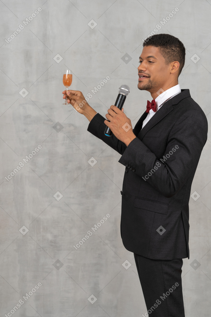 Young man with a mic and champagne glass giving a toast