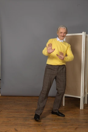 Front view of a shy smiling old man outstretching his hands