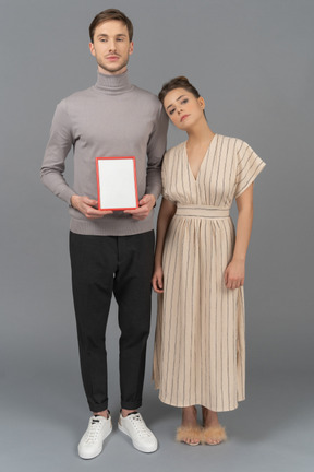 Vista frontal de um jovem casal com uma placa em branco