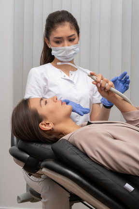 Foto de uma paciente curiosa com dentista perplexo ao fundo