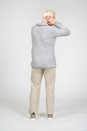 Back view of man covering his ears with his hands