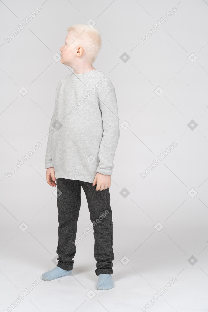 Vista frontal de um garotinho loiro olhando de lado