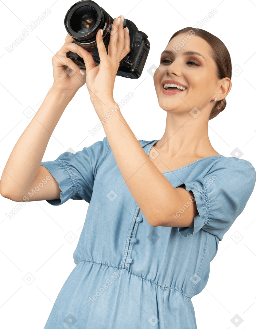 Vista frontal de uma jovem sorridente com vestido azul tirando uma foto