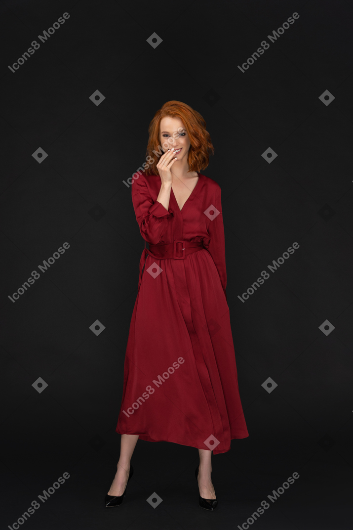 Smiling young woman in red dress touching face